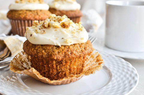 Carrot cake muffins topped with cream cheese frosting and candied carrot curls
